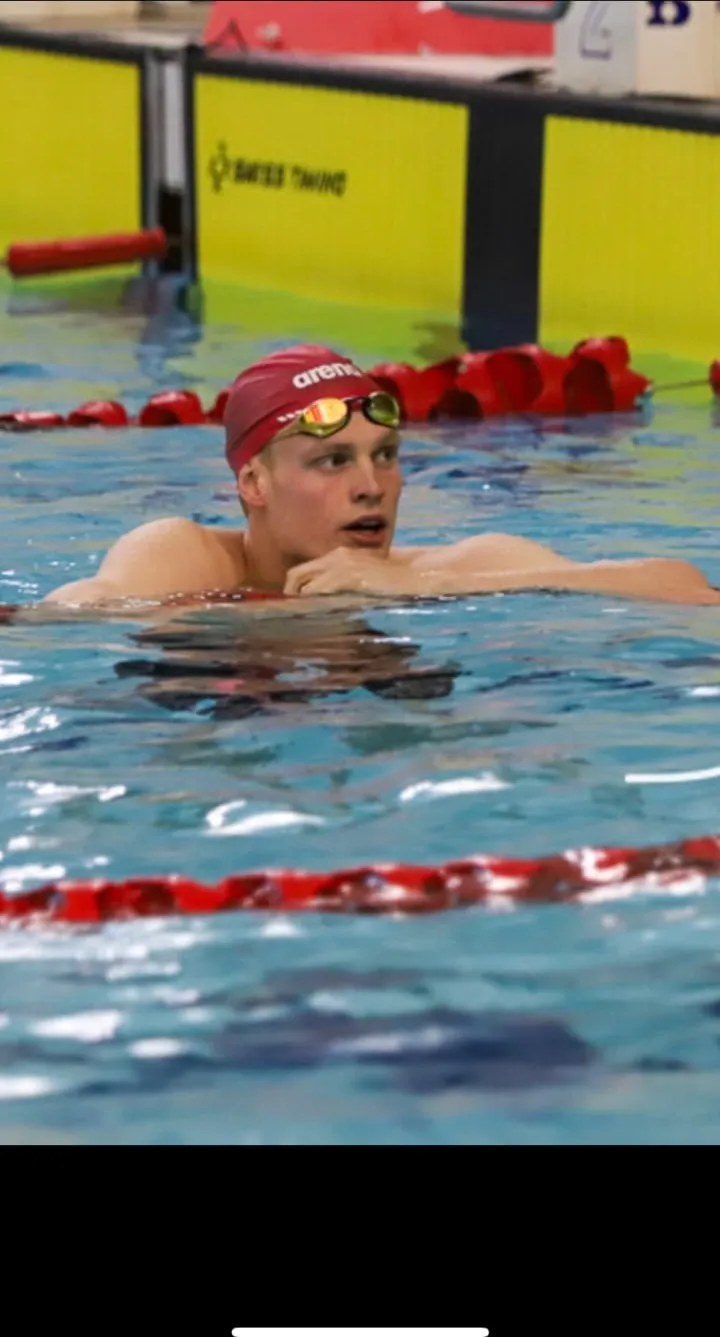 Ryan at the wall in the water after a race, looking up towards the scoreboard.